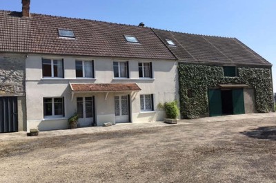 Chambre mansardée avec deux lits simples, un bureau en bois, une chaise blanche et une fenêtre de toit.