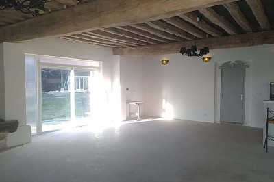 Chambre mansardée avec deux lits simples, un bureau en bois, une chaise blanche et une fenêtre de toit.