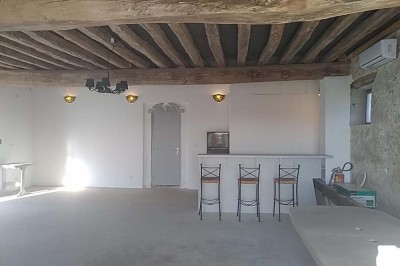 Chambre mansardée avec deux lits simples, un bureau en bois, une chaise blanche et une fenêtre de toit.