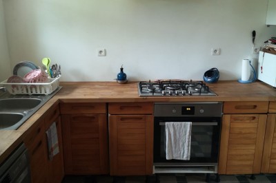 Chambre mansardée avec deux lits simples, un bureau en bois, une chaise blanche et une fenêtre de toit.