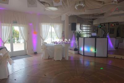 Un couple pose près d'une table décorée de fleurs et d'une pyramide de coupes de champagne dans une salle éclairée.