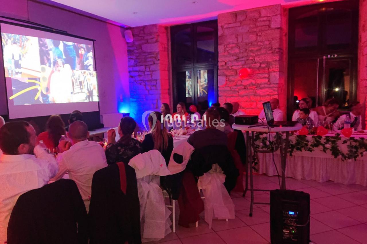 Des invités assis regardent une projection vidéo dans une salle décorée avec des lumières colorées.