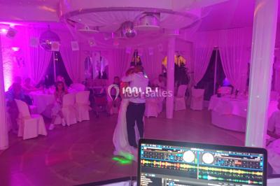 Un couple pose près d'une table décorée de fleurs et d'une pyramide de coupes de champagne dans une salle éclairée.