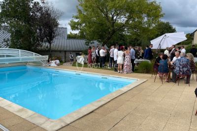 Un couple pose près d'une table décorée de fleurs et d'une pyramide de coupes de champagne dans une salle éclairée.