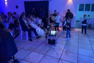 Un couple pose près d'une table décorée de fleurs et d'une pyramide de coupes de champagne dans une salle éclairée.