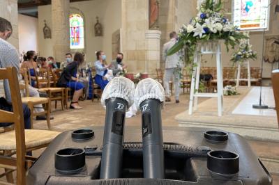 Un couple pose près d'une table décorée de fleurs et d'une pyramide de coupes de champagne dans une salle éclairée.