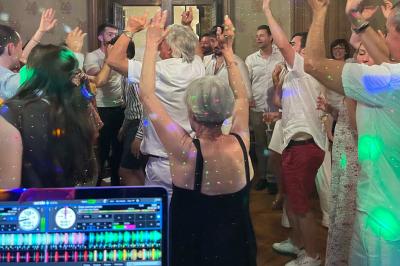 Un couple pose près d'une table décorée de fleurs et d'une pyramide de coupes de champagne dans une salle éclairée.