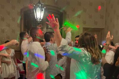 Un couple pose près d'une table décorée de fleurs et d'une pyramide de coupes de champagne dans une salle éclairée.