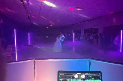 Un couple pose près d'une table décorée de fleurs et d'une pyramide de coupes de champagne dans une salle éclairée.
