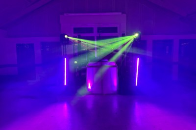 Un couple pose près d'une table décorée de fleurs et d'une pyramide de coupes de champagne dans une salle éclairée.