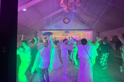 Un couple pose près d'une table décorée de fleurs et d'une pyramide de coupes de champagne dans une salle éclairée.