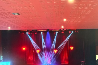 Un couple pose près d'une table décorée de fleurs et d'une pyramide de coupes de champagne dans une salle éclairée.