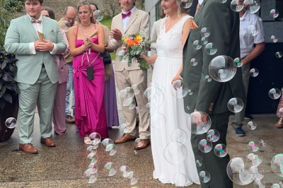 Un couple pose près d'une table décorée de fleurs et d'une pyramide de coupes de champagne dans une salle éclairée.
