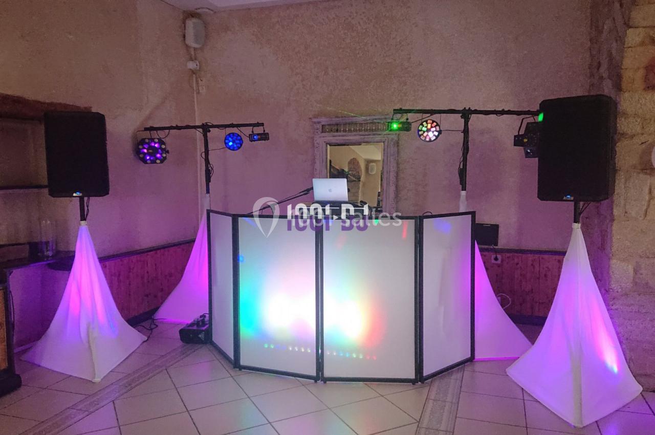 Installation de matériel de sonorisation et éclairage coloré dans une salle avec un espace DJ central.