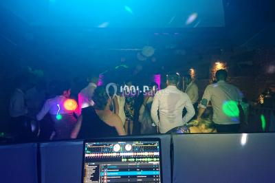 Salle en pierre avec plafond en poutres apparentes, éclairages décoratifs suspendus et équipement audio-visuel installé.