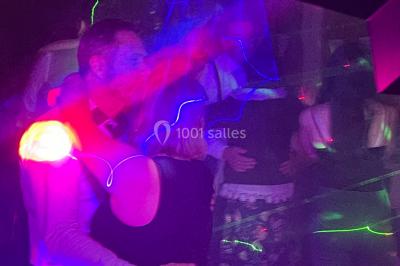 Salle en pierre avec plafond en poutres apparentes, éclairages décoratifs suspendus et équipement audio-visuel installé.