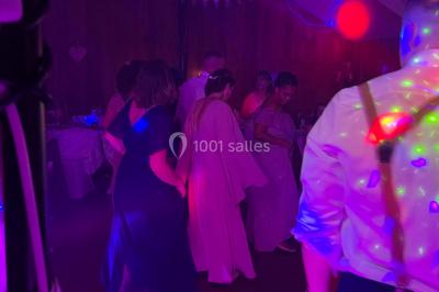 Salle en pierre avec plafond en poutres apparentes, éclairages décoratifs suspendus et équipement audio-visuel installé.