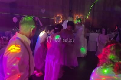 Salle en pierre avec plafond en poutres apparentes, éclairages décoratifs suspendus et équipement audio-visuel installé.