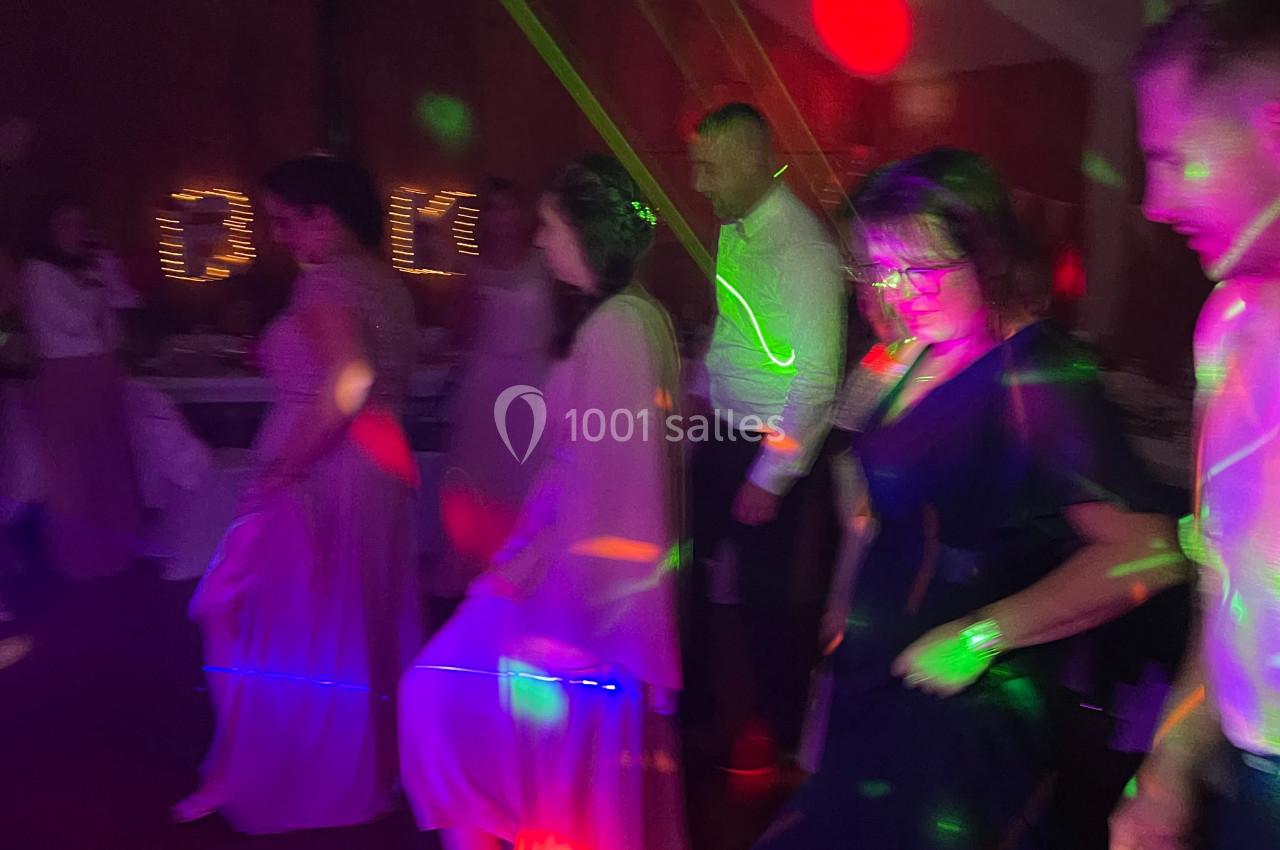 Des personnes dansent en ligne dans une salle sombre éclairée par des lumières colorées.