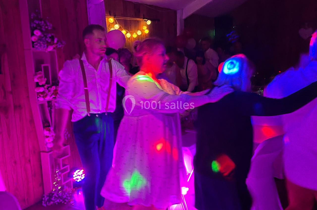 Des personnes dansent en file sous des lumières colorées dans une salle décorée pour une fête.