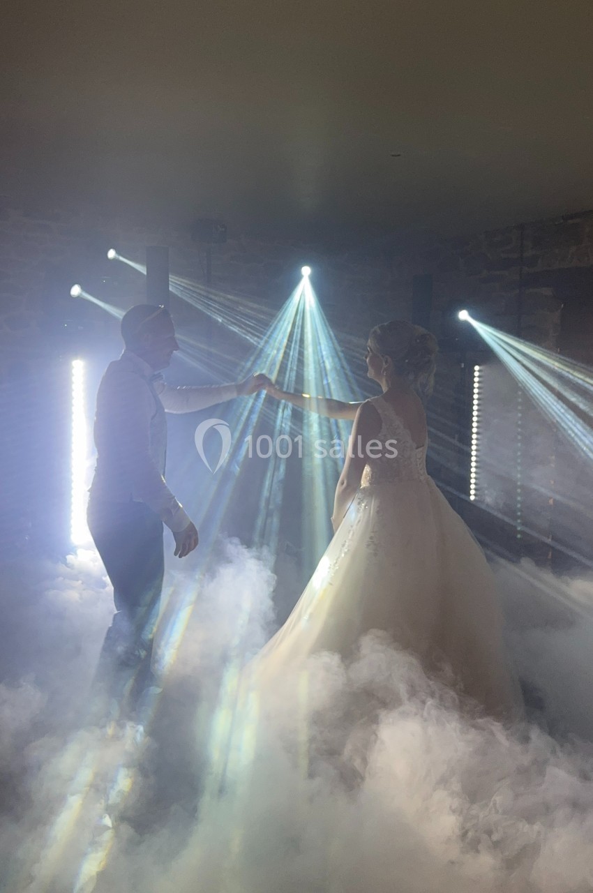 Un couple danse dans une ambiance lumineuse avec des faisceaux lumineux et un sol recouvert de fumée.