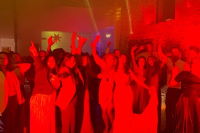 Salle en pierre avec plafond en poutres apparentes, éclairages décoratifs suspendus et équipement audio-visuel installé.