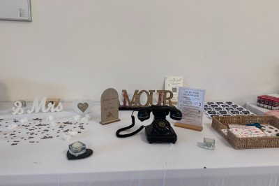 Salle en pierre avec plafond en poutres apparentes, éclairages décoratifs suspendus et équipement audio-visuel installé.