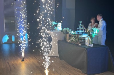 Salle en pierre avec plafond en poutres apparentes, éclairages décoratifs suspendus et équipement audio-visuel installé.