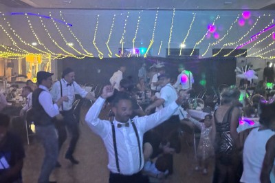 Salle en pierre avec plafond en poutres apparentes, éclairages décoratifs suspendus et équipement audio-visuel installé.