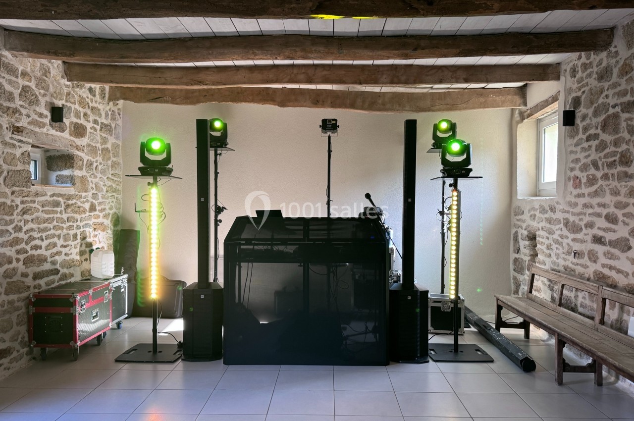 Installation de matériel de sonorisation et d'éclairage dans une salle en pierre avec poutres apparentes.