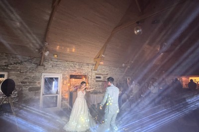 Salle en pierre avec plafond en poutres apparentes, éclairages décoratifs suspendus et équipement audio-visuel installé.