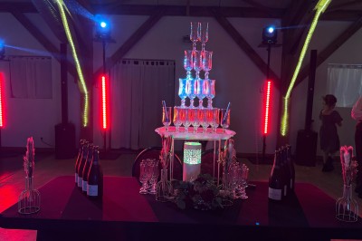 Salle en pierre avec plafond en poutres apparentes, éclairages décoratifs suspendus et équipement audio-visuel installé.