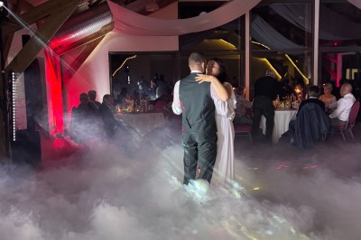 Salle en pierre avec plafond en poutres apparentes, éclairages décoratifs suspendus et équipement audio-visuel installé.