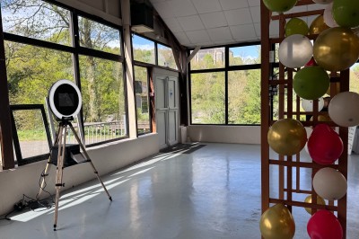 Installation de matériel de son et lumière dans une salle de réception lumineuse avec tables dressées.