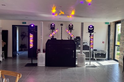 Installation de matériel de son et lumière dans une salle de réception lumineuse avec tables dressées.