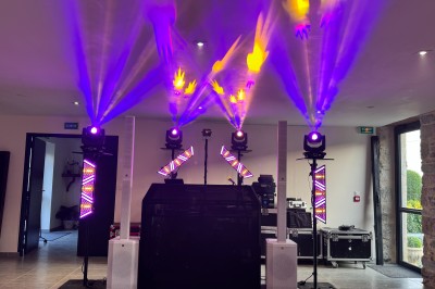 Installation de matériel de son et lumière dans une salle de réception lumineuse avec tables dressées.