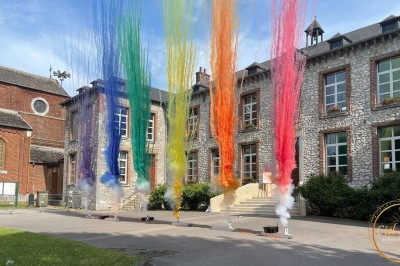 Salle en pierre avec plafond en poutres apparentes, éclairages décoratifs suspendus et équipement audio-visuel installé.