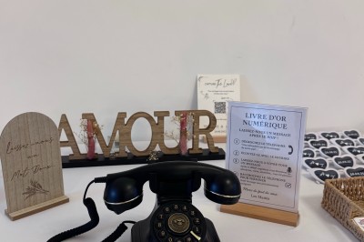 Salle en pierre avec plafond en poutres apparentes, éclairages décoratifs suspendus et équipement audio-visuel installé.