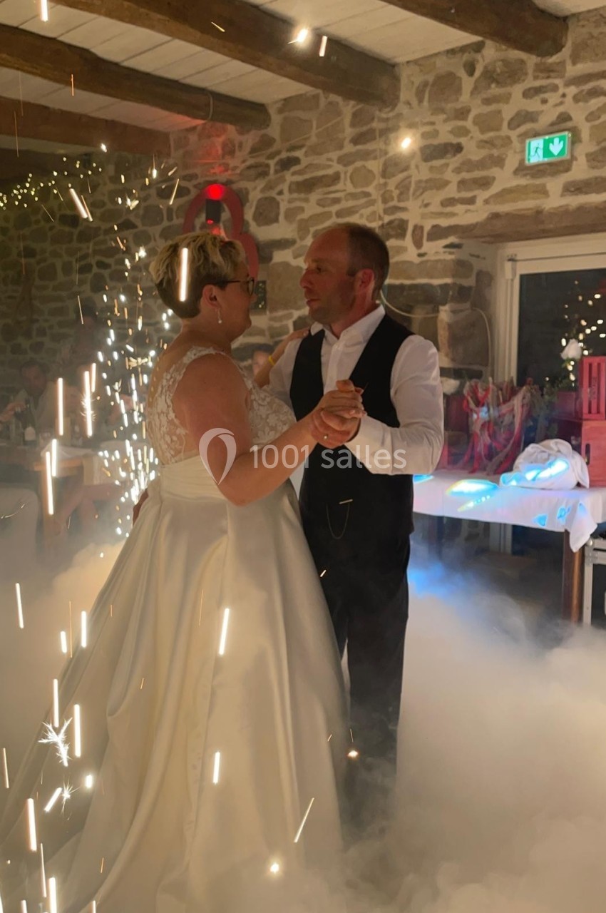 Un couple danse dans une salle en pierre illuminée, entouré d'effets de lumière et de fumée.