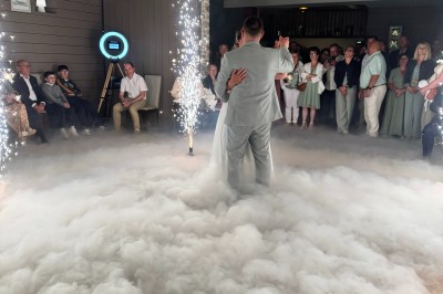 Salle en pierre avec plafond en poutres apparentes, éclairages décoratifs suspendus et équipement audio-visuel installé.