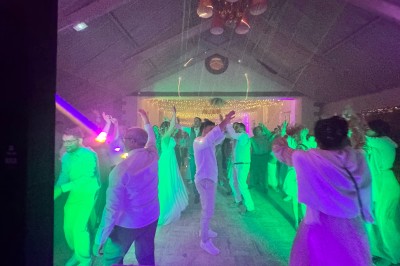 Salle en pierre avec plafond en poutres apparentes, éclairages décoratifs suspendus et équipement audio-visuel installé.