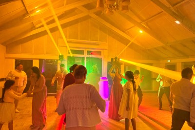 Salle en pierre avec plafond en poutres apparentes, éclairages décoratifs suspendus et équipement audio-visuel installé.