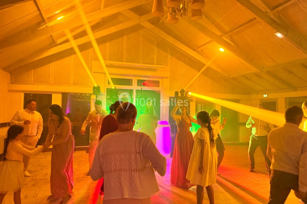 Des personnes dansent dans une salle éclairée par des lumières colorées, créant une ambiance festive.