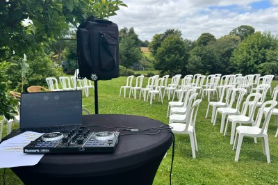 Salle en pierre avec plafond en poutres apparentes, éclairages décoratifs suspendus et équipement audio-visuel installé.