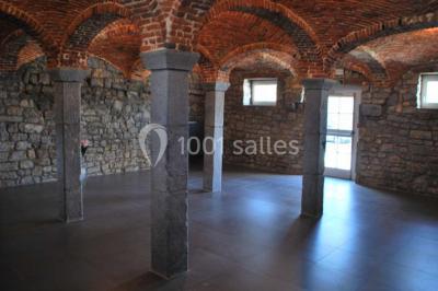 Voûtes en briques rouges soutenues par des colonnes en pierre dans une pièce au sol carrelé.