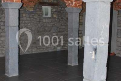 Voûtes en briques rouges soutenues par des colonnes en pierre dans une pièce au sol carrelé.