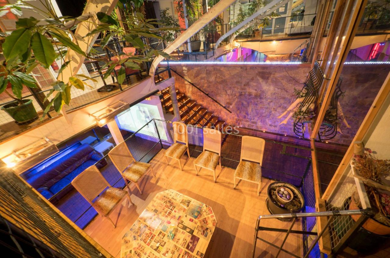 Vue intérieure d'un espace aménagé avec des chaises, une table basse et des plantes, éclairé par des lumières chaleureuses.