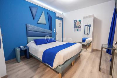 Chambre d'hôtel moderne avec lit double, murs verts, salle de bain attenante et mobilier contemporain.