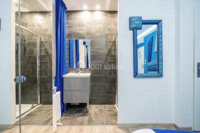 Chambre d'hôtel moderne avec lit double, murs verts, salle de bain attenante et mobilier contemporain.