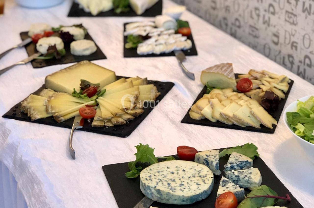 Plateaux de fromages variés présentés sur une table, accompagnés de tomates cerises et de feuilles de salade.